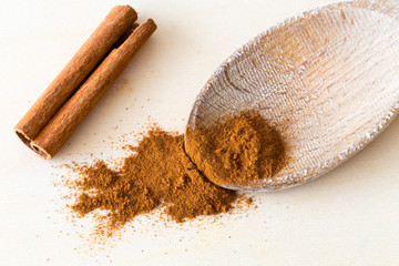 Cinnamon spice as bark stick and ground powder on wooden spoon