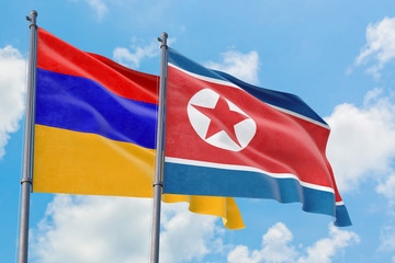 North Korea and Armenia flags waving in the wind against white cloudy blue sky together. Diplomacy concept, international relations.