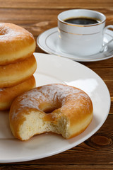 donuts with a bite and cup of coffee at back vertical composition
