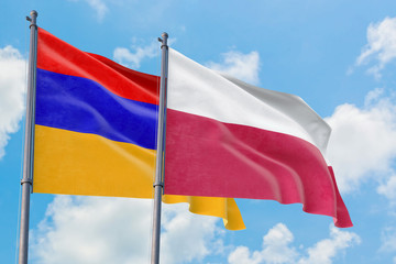 Poland and Armenia flags waving in the wind against white cloudy blue sky together. Diplomacy concept, international relations.