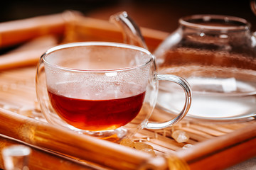 Cup of hot tea with rock sugar, dry leaves served in thermo glass cup