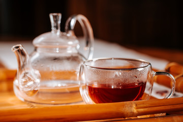 Cup of hot tea with rock sugar, dry leaves served in thermo glass cup