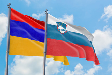 Slovenia and Armenia flags waving in the wind against white cloudy blue sky together. Diplomacy concept, international relations.