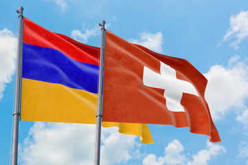 Switzerland and Armenia flags waving in the wind against white cloudy blue sky together. Diplomacy concept, international relations.