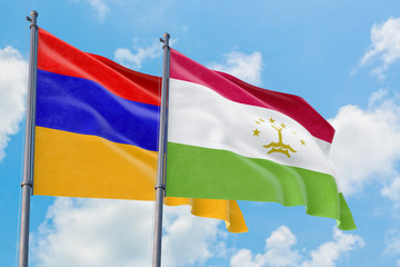 Tajikistan and Armenia flags waving in the wind against white cloudy blue sky together. Diplomacy concept, international relations.