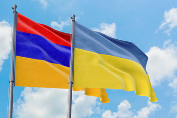 Ukraine and Armenia flags waving in the wind against white cloudy blue sky together. Diplomacy concept, international relations.