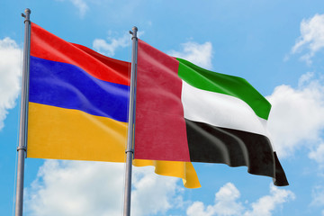 United Arab Emirates and Armenia flags waving in the wind against white cloudy blue sky together. Diplomacy concept, international relations.