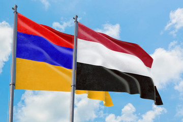 Yemen and Armenia flags waving in the wind against white cloudy blue sky together. Diplomacy concept, international relations.