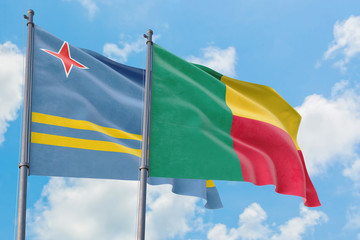 Benin and Aruba flags waving in the wind against white cloudy blue sky together. Diplomacy concept, international relations.