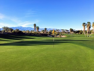A behind the green view of a beautiful golf hole and green with the mountains in the background in...