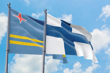 Finland and Aruba flags waving in the wind against white cloudy blue sky together. Diplomacy concept, international relations.