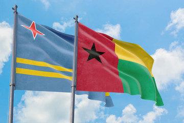 Guinea Bissau and Aruba flags waving in the wind against white cloudy blue sky together. Diplomacy concept, international relations.