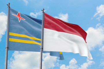 Fototapeta na wymiar Indonesia and Aruba flags waving in the wind against white cloudy blue sky together. Diplomacy concept, international relations.