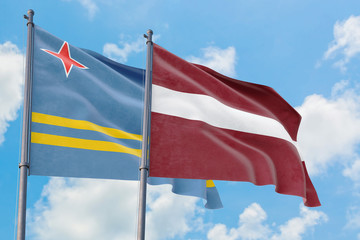 Latvia and Aruba flags waving in the wind against white cloudy blue sky together. Diplomacy concept, international relations.