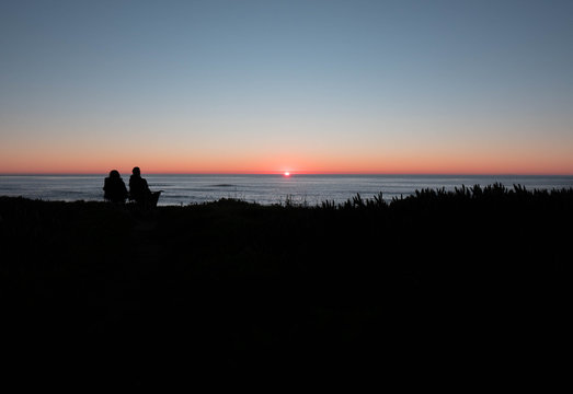 silhouette of a couple looking at the sunset over the cliffs valentine day concept
