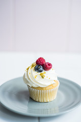Cupcake with white cream and berries on the table