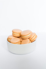 Orange macaron in a white plate on a white isolated background