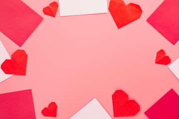 The red paper heart shapes and envelope over the pink pastel background. Greeting cards, Love and Valentines day concept. Flat lay, top view, copy space.