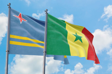 Senegal and Aruba flags waving in the wind against white cloudy blue sky together. Diplomacy concept, international relations.