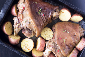 pork knuckle and potatoes on a baking sheet