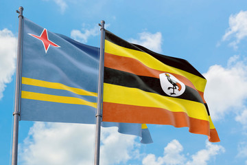 Uganda and Aruba flags waving in the wind against white cloudy blue sky together. Diplomacy concept, international relations.