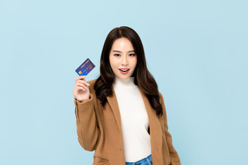 Beautiful smiling Asian woman showing credit card in hand
