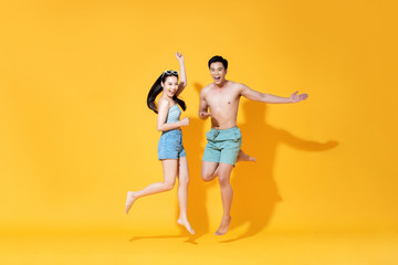 Fototapeta na wymiar Energetic happy Asian couple in summer beach casual clothes jumping