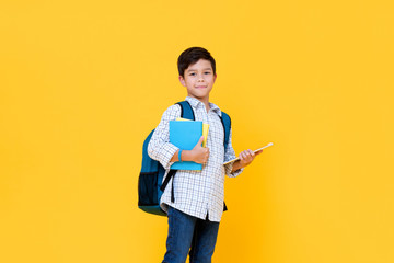 Fototapeta Handsome schoolboy with backpack holding books and tablet computer obraz
