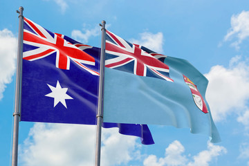 Fiji and Australia flags waving in the wind against white cloudy blue sky together. Diplomacy concept, international relations.