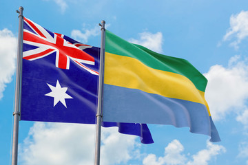 Gabon and Australia flags waving in the wind against white cloudy blue sky together. Diplomacy concept, international relations.