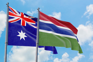 Gambia and Australia flags waving in the wind against white cloudy blue sky together. Diplomacy concept, international relations.
