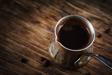 Copper cezve with coffee on wooden table, copy space