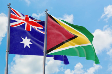 Guyana and Australia flags waving in the wind against white cloudy blue sky together. Diplomacy concept, international relations.