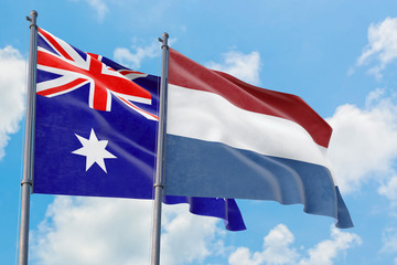 Netherlands and Australia flags waving in the wind against white cloudy blue sky together. Diplomacy concept, international relations.