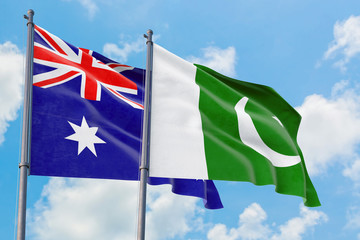 Fototapeta premium Pakistan and Australia flags waving in the wind against white cloudy blue sky together. Diplomacy concept, international relations.