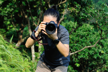 Fototapeta premium Photographer taking photo in the forest with digital camera