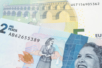A blue and green, European five euro bank note with a blue two thousand peso note from Colombia close up in macro