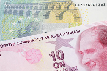 A red ten Turkish lira bill close up in macro with a red, European five Euro note 