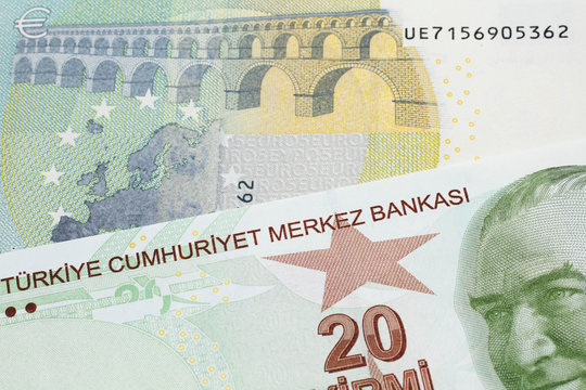 A close up image of a red, yellow and green twenty Turkish lira bank note with a German five euro bill in macro