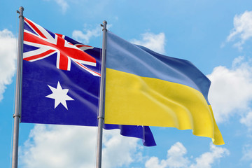 Ukraine and Australia flags waving in the wind against white cloudy blue sky together. Diplomacy...