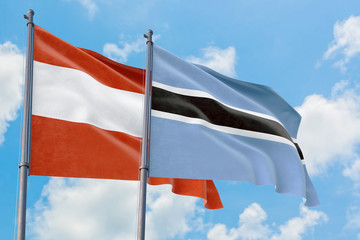 Botswana and Austria flags waving in the wind against white cloudy blue sky together. Diplomacy concept, international relations.
