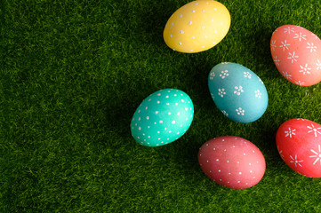 Fototapeta na wymiar Easter colored eggs on green grass, with space for congratulation. Flat lay