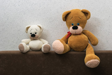 Large and small bears on the back of the sofa near the textured wall.