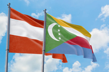 Comoros and Austria flags waving in the wind against white cloudy blue sky together. Diplomacy concept, international relations.
