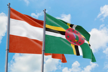 Dominica and Austria flags waving in the wind against white cloudy blue sky together. Diplomacy...