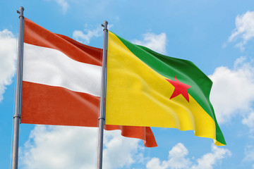 French Guiana and Austria flags waving in the wind against white cloudy blue sky together. Diplomacy concept, international relations.