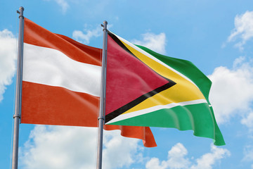 Guyana and Austria flags waving in the wind against white cloudy blue sky together. Diplomacy concept, international relations.