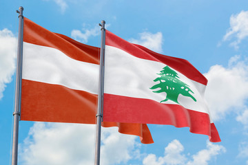Lebanon and Austria flags waving in the wind against white cloudy blue sky together. Diplomacy concept, international relations.
