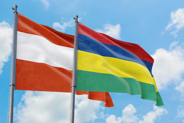 Mauritius and Austria flags waving in the wind against white cloudy blue sky together. Diplomacy concept, international relations.