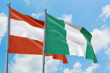 Nigeria and Austria flags waving in the wind against white cloudy blue sky together. Diplomacy concept, international relations.